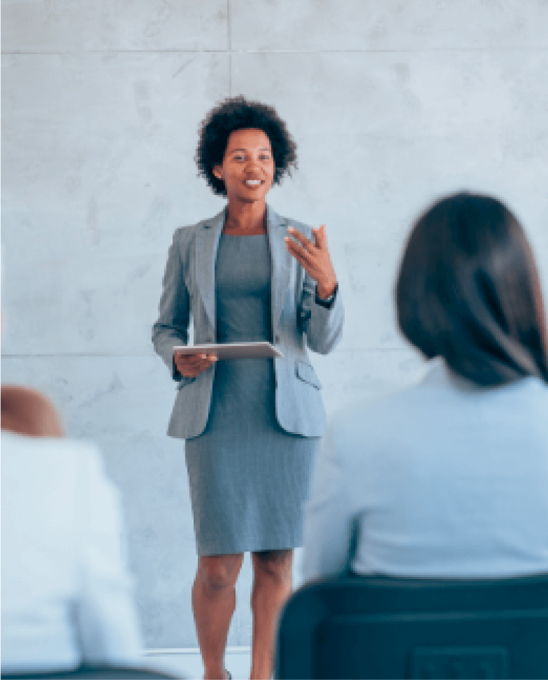 Woman holding papers and speaking in front of an audience